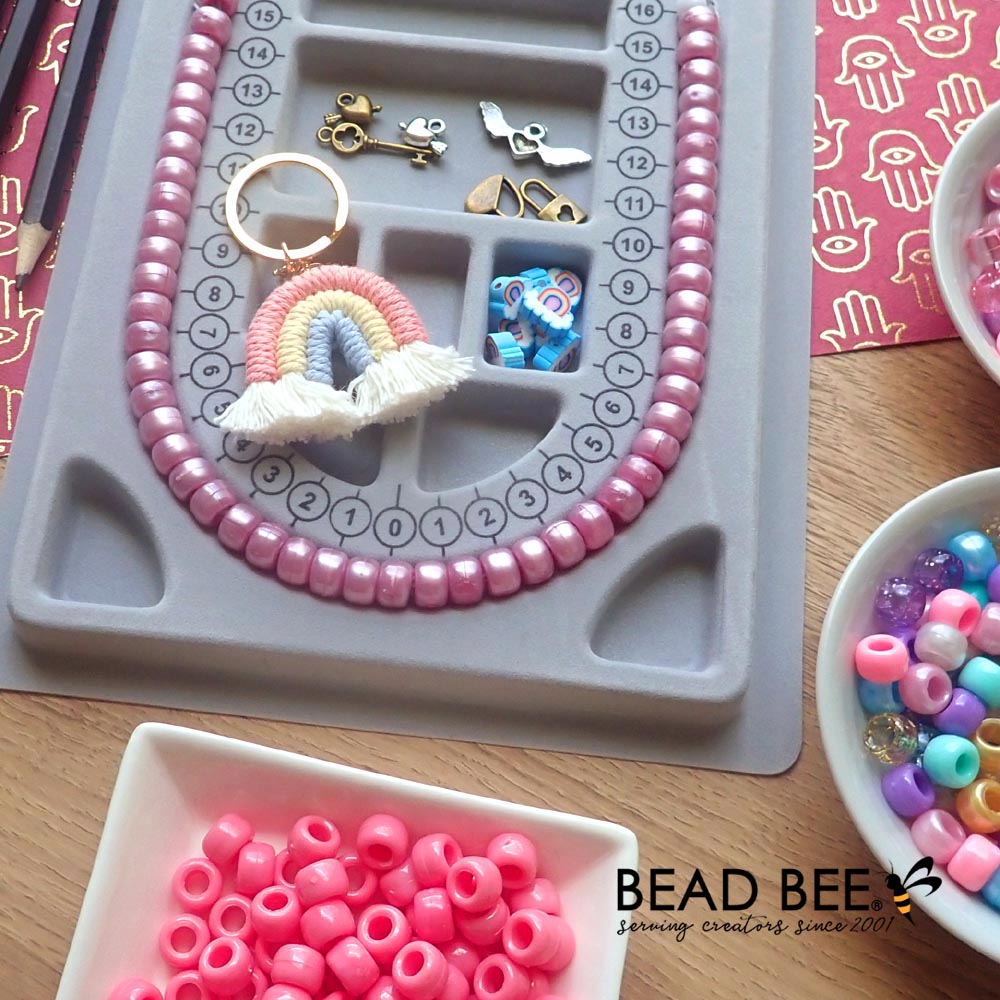 mauve pearl pony beads displayed on a bead board with other beads and crafts supplies on table